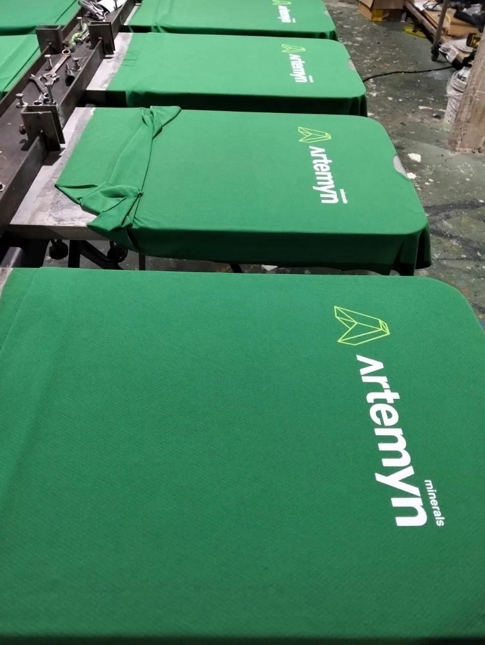 Camisetas verdes estampadas com logotipo de empresa sobre a mesa de produção
